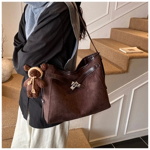 Macro view of dark brown suede tote with silver twist lock and cute knitted bear charm