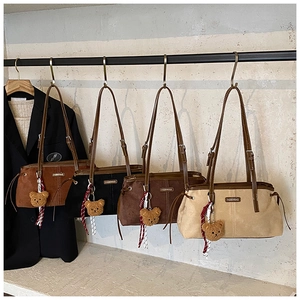 Detailed display of four faux suede hobo bags in assorted colors with bear charms