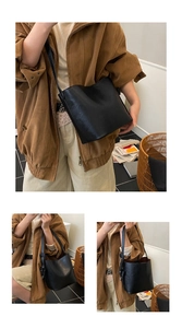 Close-up of a black leather bucket bag showing its premium texture and drawstring details