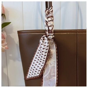 Close-up of decorative silk scarf with 3D geometric patterns tied on a brown tote bag handle