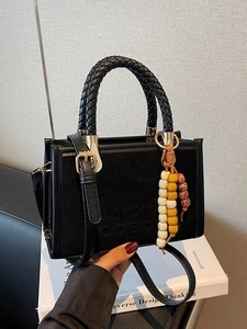 Black suede tote bag with woven handles, bead charm, and adjustable shoulder strap