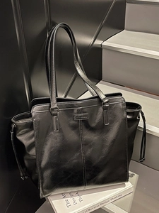 Classic black tote bag in glossy faux leather with long shoulder straps for daily commuting