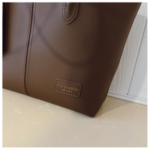 Close-up of brown leather tote bag texture with elegant gold foil stamped label