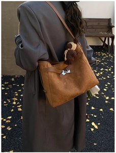 Close-up of brown suede tote bag with silver clasp and cute plush bear charm