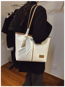 Detail of off-white leather tote bag with brown straps and stylish silk scarf decoration
