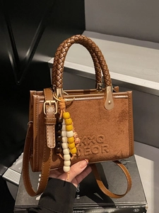 Brown suede handbag with woven handle and colorful beaded charm for autumn style