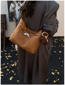 Detail of vintage brown suede tote bag with silver twist lock and knit bear charm