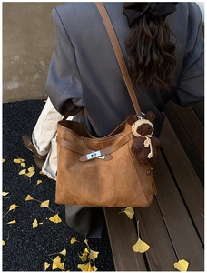 Brown vintage faux suede tote bag with silver buckle and bear charm in autumn setting