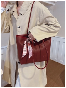 Deep red leather tote bag styled with a floral silk scarf on a beige trench coat