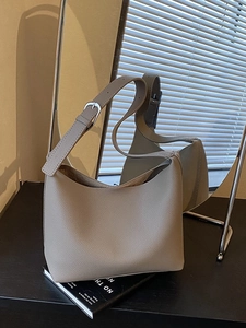 Large beige pebbled leather hobo bag on books with adjustable shoulder strap and silver buckle