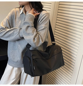 Detail of black cylinder fitness bag with wide strap and side zipper pocket for travel
