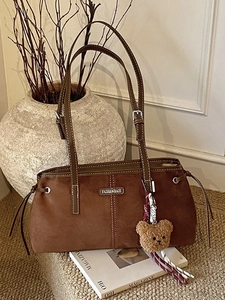 Retro brown faux suede shoulder bag with bear pendant and white stitching on magazines