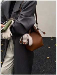Sac seau en cuir marron avec poignée foncée et détail de breloque lapin en peluche gris