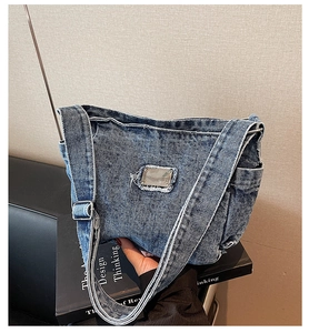 Detailed close-up of retro washed denim shoulder bag with metal logo and frayed edges