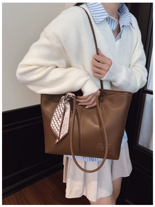 Detail of vintage brown leather tote bag featuring a decorative patterned silk scarf handle