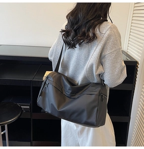 Detail of black large capacity shoulder bag with matte waterproof fabric and textile strap