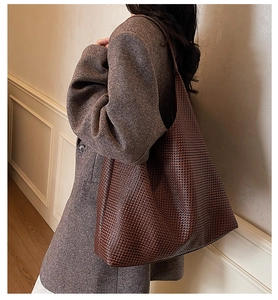 Close-up of woven shoulder bag in dark brown with textured finish on model