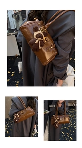 Detail der dunkelbraunen glänzenden Schultertasche mit Teddybär-Anhänger und Goldschnalle