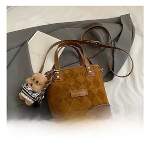 Close-up of brown frosted bucket bag with quilted stitching and a cute bear charm