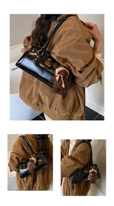 Detail einer schwarzen Lackleder-Baguette-Tasche mit Goldschloss und Bärchen