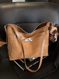 Retro brown suede tote bag with metal lock and bear charm on a leather seat