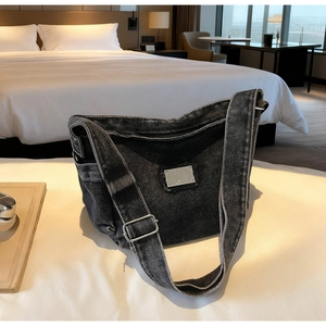Detail of vintage black denim tote bag with metal buckle and washed fabric texture