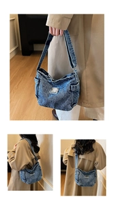 Detail of blue denim shoulder bag showing vintage washed texture and side pocket design