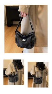 Detail of vintage black denim shoulder bag with side pockets and metal plaque logo