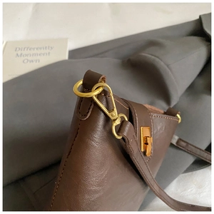 Detail of vintage gold D-ring and lobster clasp on dark brown leather bucket bag