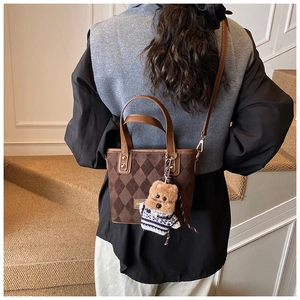 Detail of vintage matte brown bucket bag featuring diamond patterns and a cute bear charm