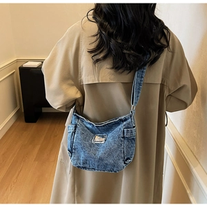 Back view of a model wearing a washed blue denim tote bag in a cozy indoor setting