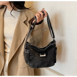 Detail of vintage washed black denim tote bag with cargo pockets and metal buckle on model