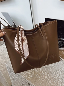 Brown faux leather tote bag with decorative sunflower scarf and metal fashion label