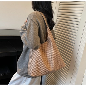 Close-up of large woven houndstooth tote bag with brown leather shoulder strap