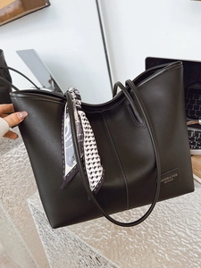 Black leather tote bag with decorative silk scarf and spacious interior for daily commute