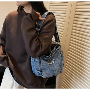 Detail of blue denim tote bag featuring functional side pockets and wide shoulder strap