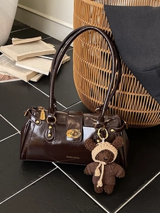 Dunkelbraune glänzende Baguette-Tasche mit goldenem Drehverschluss und Teddybär-Anhänger