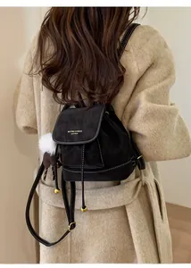 Dettaglio di un mini zaino vintage in pelle nera con finiture dorate e ciondoli
