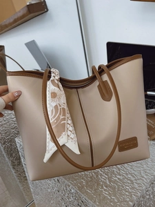 Chic beige tote bag with brown trim, silk scarf decoration, and professional office background