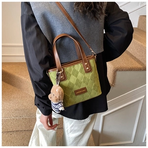 Detail of dark green quilted bucket bag with leather trim and plush bear charm