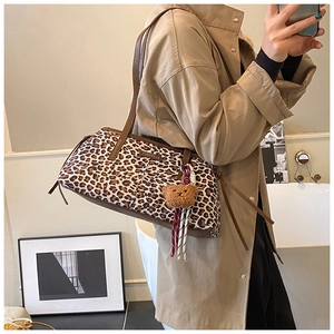Detail of leopard print underarm bag with a cute bear pendant and fashion brand label