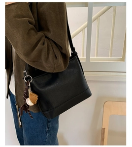 Seitenansicht der schwarzen matten Leder-Eimertasche mit sportlichem Baseball-Anhänger
