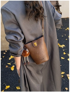 Detail of vintage brown leather bucket bag with gold buckle and leopard plush charm