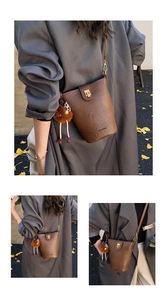 Close-up of retro brown bucket bag with plush charm and metal buckle hardware detail