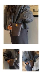 Detail view of coffee leather bucket bag with gold metal lock and plush doll charm