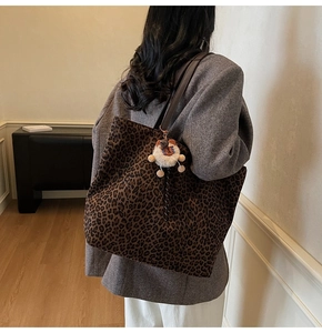 Detail of leopard print tote bag with brown leather strap and plush bear charm
