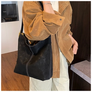 Detail of black matte tote bag featuring contrast white stitching and gold buckles