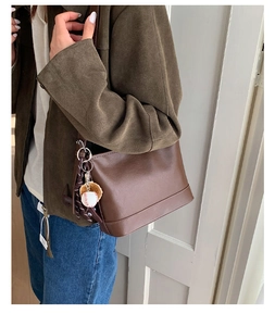 Detail einer dunkelbraunen Vintage-Beuteltasche mit einem dekorativen Baseballhandschuh-Anhänger