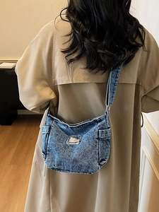 Vintage blue washed denim crossbody bag with adjustable strap worn with a khaki coat