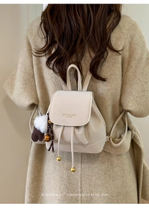 Dettaglio mini zaino in pelle scamosciata beige con coulisse e ciondolo a pompon